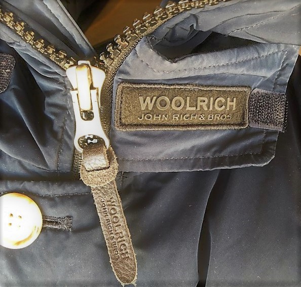 ブログ「モノオス」WOOLRICH(ウールリッチ）アークティックパーカのジッパーと、首もとにあるジッパー止めのタグを映した写真（ジッパー止めで止めていない）